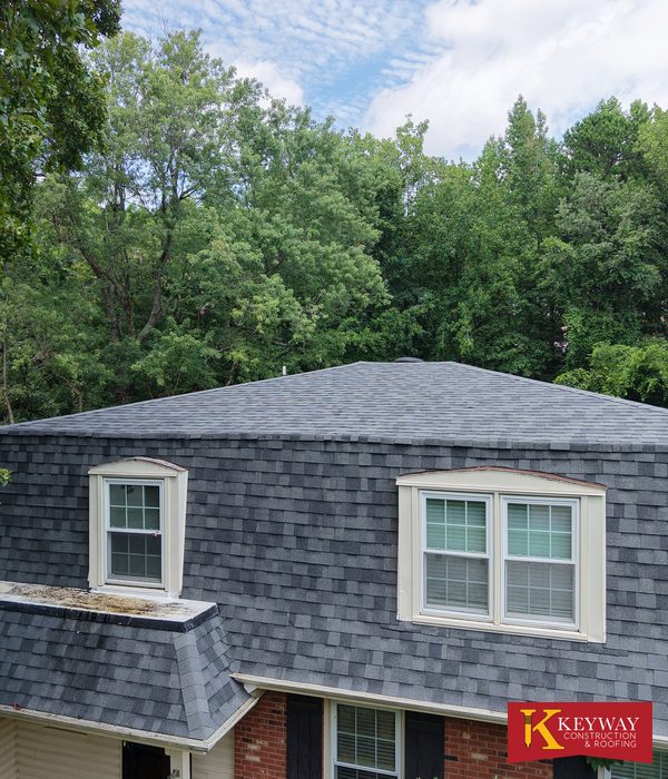 Steep mansard roof face on a Charlotte NC home covered in new gray architectural shingles with two white trimmed dormer windows