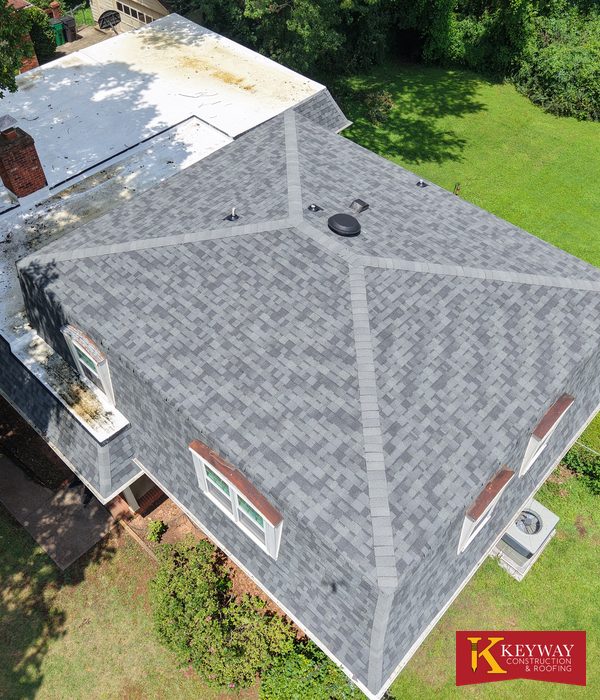 Drone view of a Charlotte NC home with a new gray shingle roof, ridge lines and bright white flat roof sections after replacement