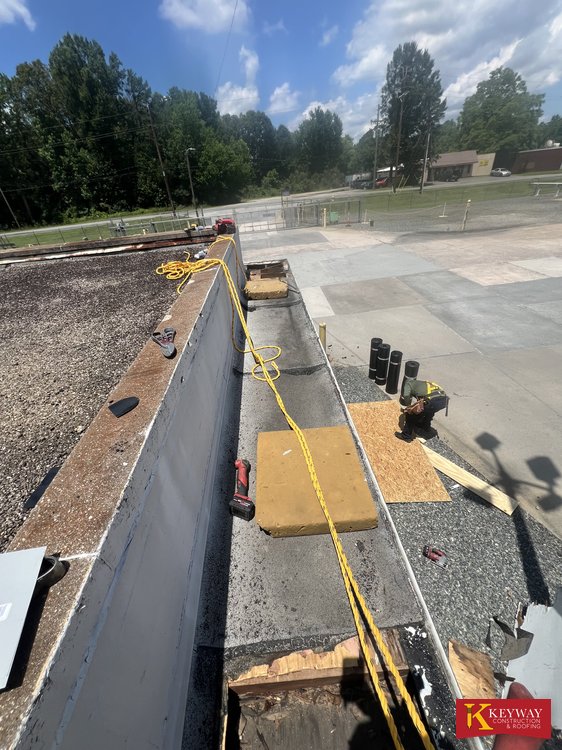 Parapet wall along a commercial flat roof with sections removed for repair