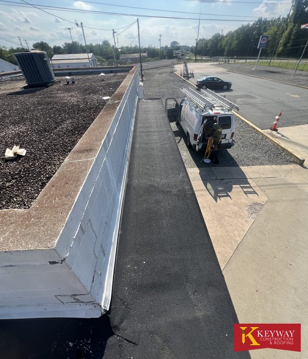 Commercial flat roof parapet wall rewrapped in white membrane with new dark membrane along its base after a Keyway repair