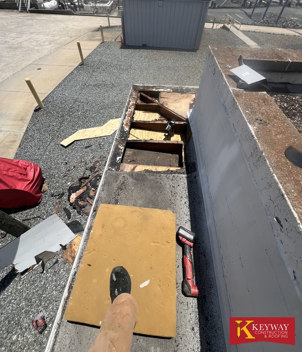 Commercial flat roof parapet wall opened up to show rotted wood framing and wet decking before Keyway made the repair