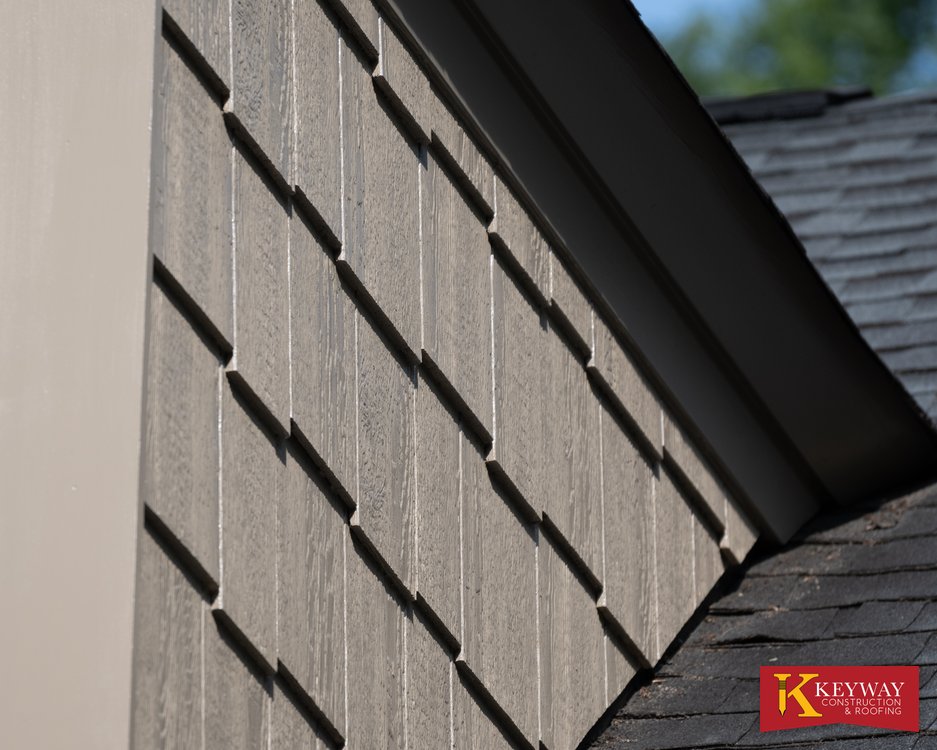 Close up of new dormer corner trim and shake style siding meeting the shingled roof