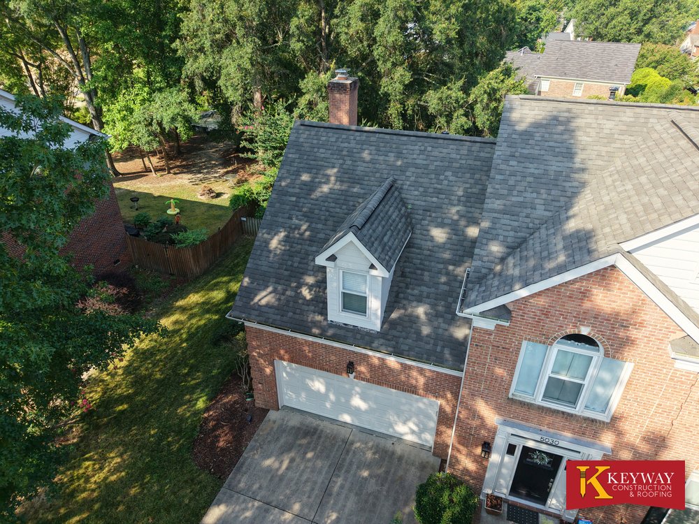 New shingles around a front dormer and brick chimney on a Matthews NC home