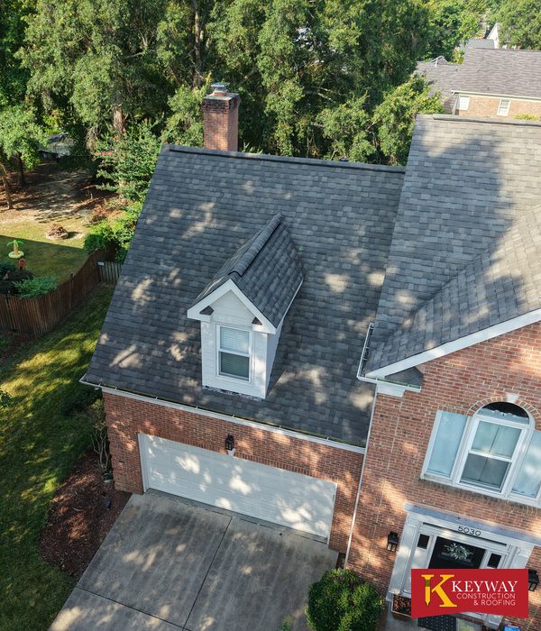 Brick Matthews NC home with new charcoal architectural shingles around its front dormers and chimney after a Keyway roof replacement