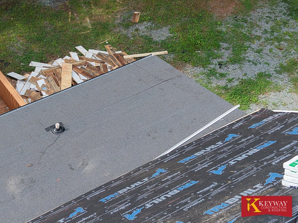 Low slope roof membrane with a pipe flashing meeting the shingled main roof in Monroe NC