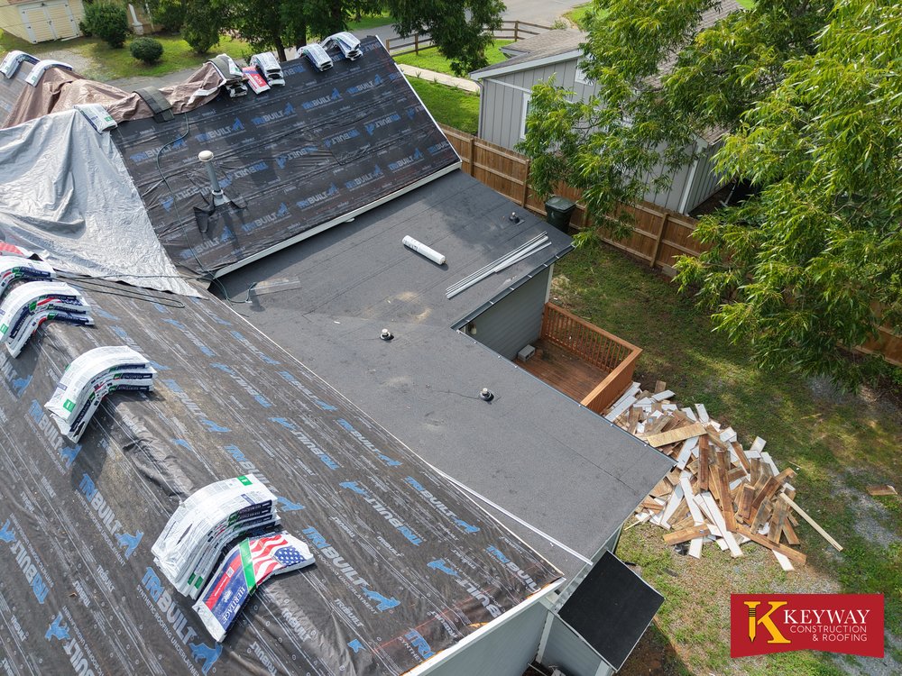New granulated low slope roof sections beside synthetic underlayment on a Monroe NC house