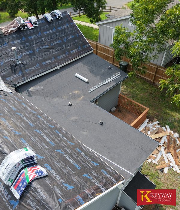 New low slope roof section on a Monroe NC house tying into a main roof prepared with synthetic underlayment and shingle bundles